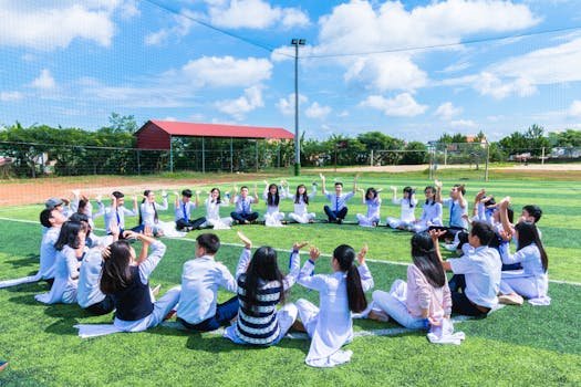 Students seated in a circle on a school field engaging in outdoor activities.